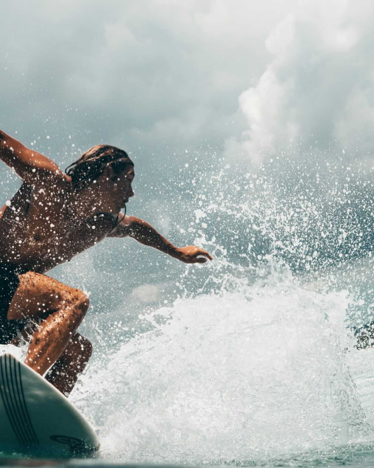 Energetic surfer rides ocean waves in tropical Indonesia, capturing the thrill of water sports.