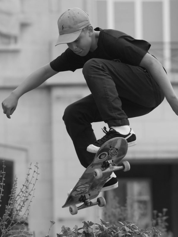 A young male skater in mid-air performing a jump with a skateboard outdoors.